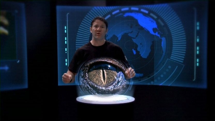 Steve Backshall in front of high tech blue screen with a crocodile's eye the screen.
