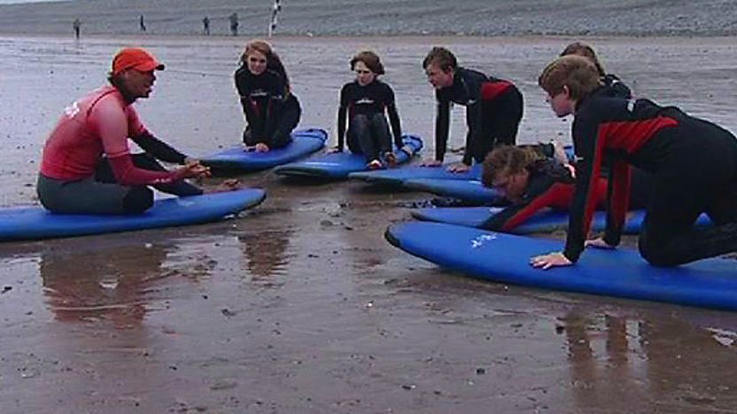 A group of children on the beach being taught to surf