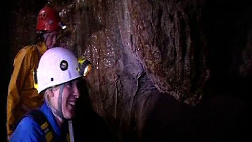 Naomi Wilkinson wearing a headtorch and exploring a cave 