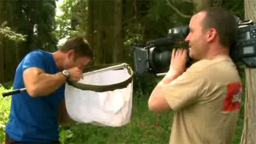 Steve Backshall looking in a massive net whilst a cameraman films him