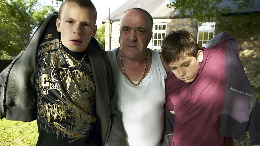 dad carrying two boys by collars