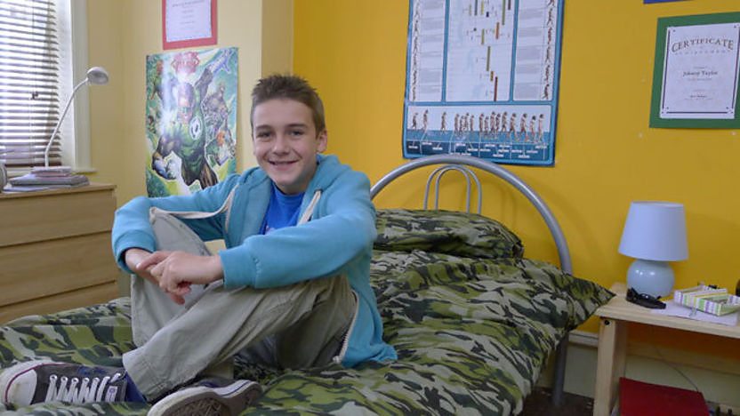 Image of Johnny sitting on his bed.