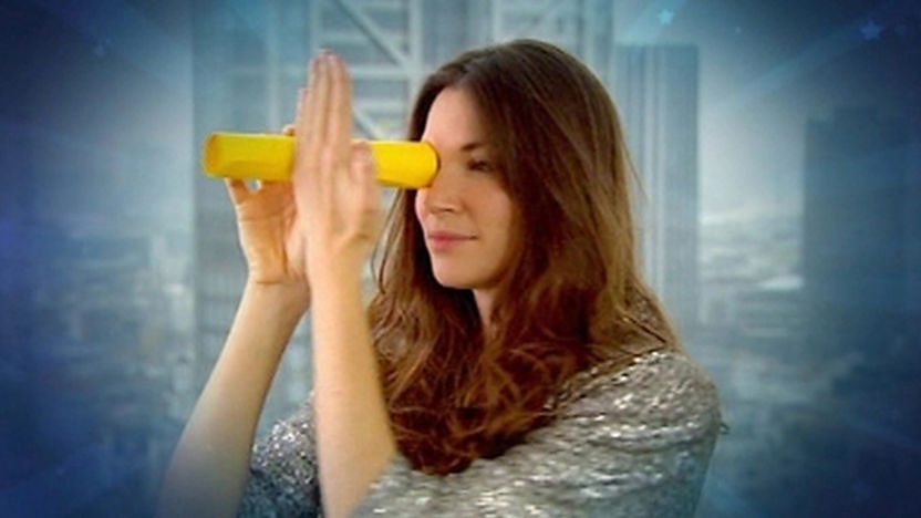 Katherine holding a tube to her eye next to her hand.