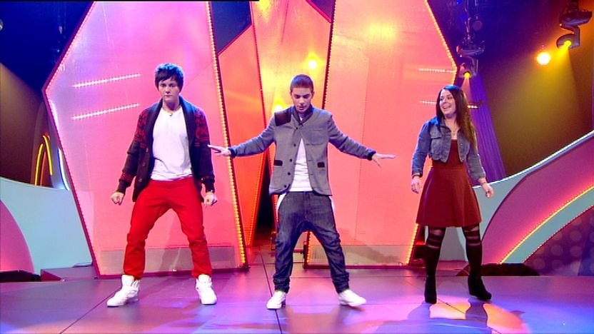 Aidan Davis, Dani Harmer and Tyger Drew-Honey on stage dancing. 