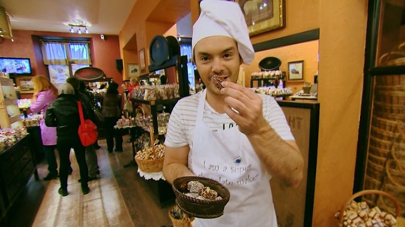 Barney Harwood holding a chocolate in a chocolate factory