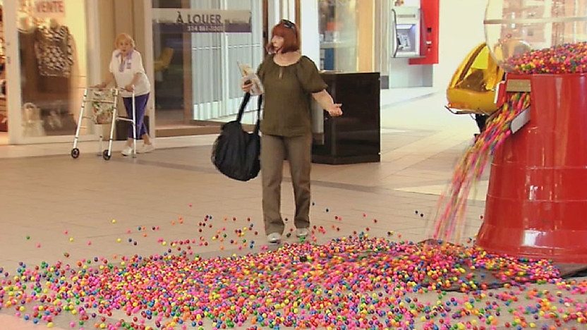 Woman stood beside faulty bubblegum machine.