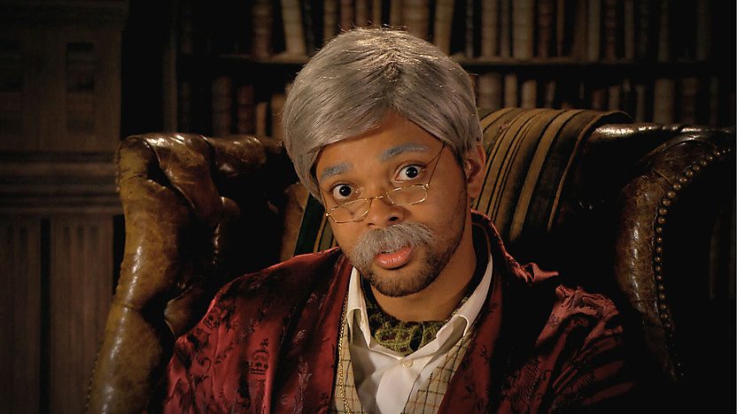 Johnny dressed as an old man in a library.