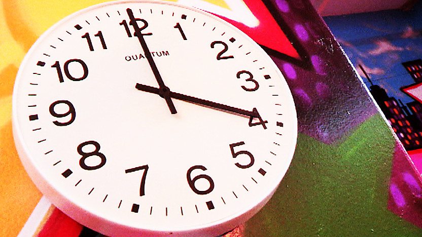 A clock on a colourful wall that reads 4 O'Clock.