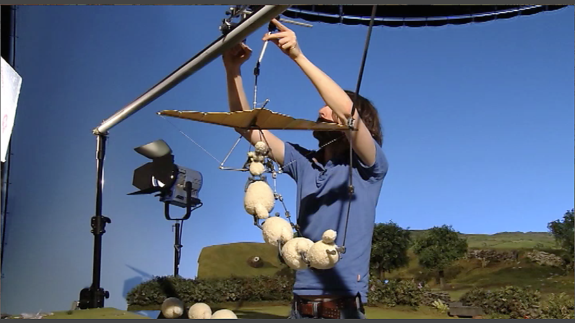 An animator holding up the shaun the sheep characters with rigging.