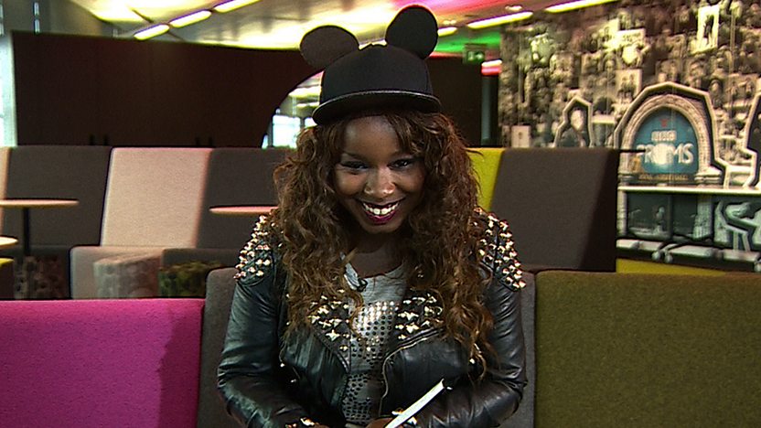 Misha B sitting on sofa looking at camera
