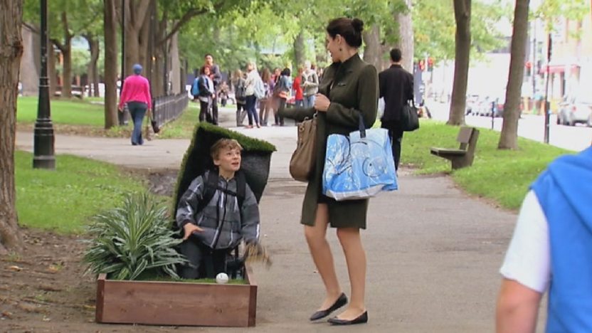 Woman being surprised by boy underneath grass.