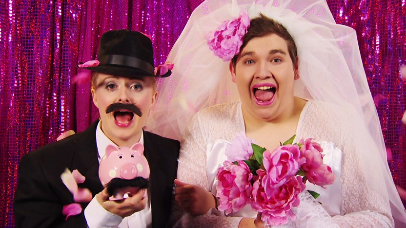 CBBC Office presenters Chris and Katie dressed as a married couple, hilariously though, Chris is the lipsticked bride and Katie is the moustachioed groom.