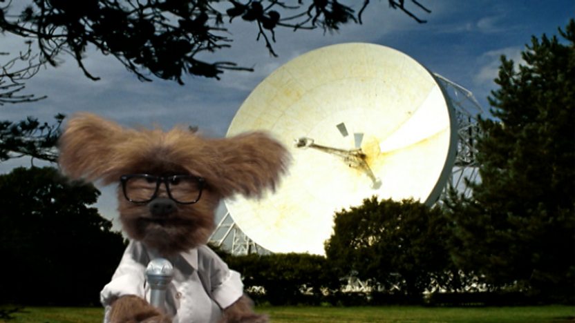 Dodge dressed as a reporter next to a satellite dish