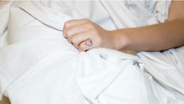Una mano con un tatuaje que agarra una sábana