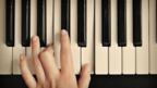 A hand plays a piano