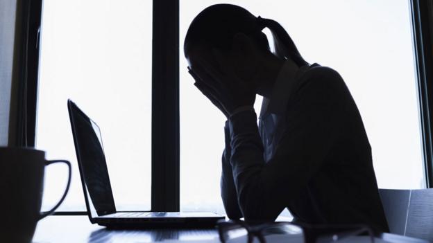 Woman with head in hands in front of computer (Thinkstock)