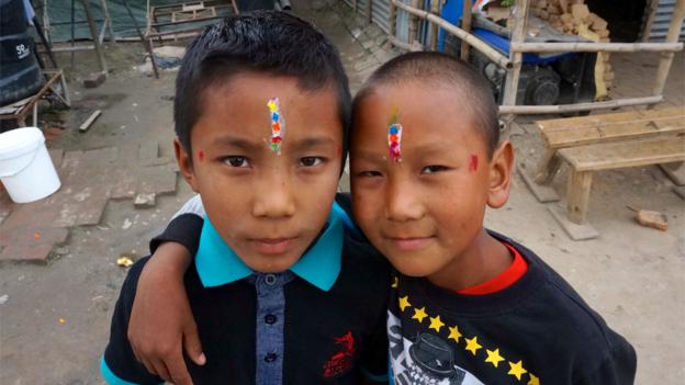 Grinning brothers, with multi-coloured tikas on their foreheads 