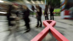 People walk past an AIDS ribbon (copyright: Getty Images)