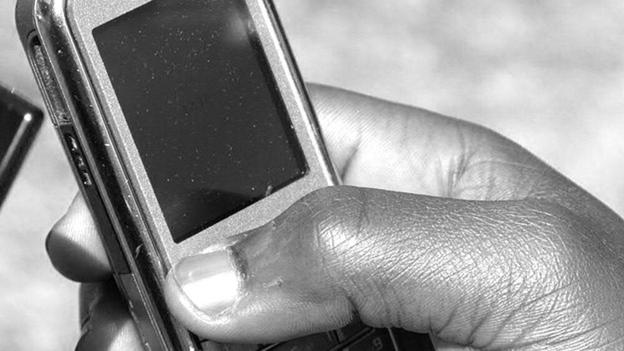 Hand on a phone in Zambia (Image used under Creative Commons from mLeanring Africa)