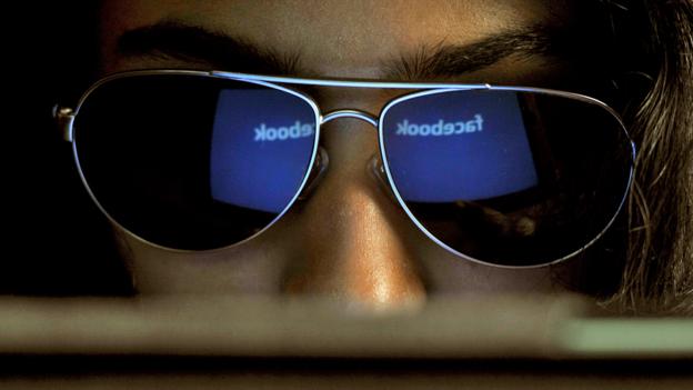 Girl looks at Faccebook page wearing sunglasses (Copyright: Getty Images)