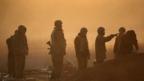 Israeli soldiers prepare a shell amongst smoke as an artillery emplacement fires into Gaza