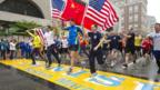 Runners holding three American flags and one Chinese cross the finish line of the Boston Marathon (25 May 2013)