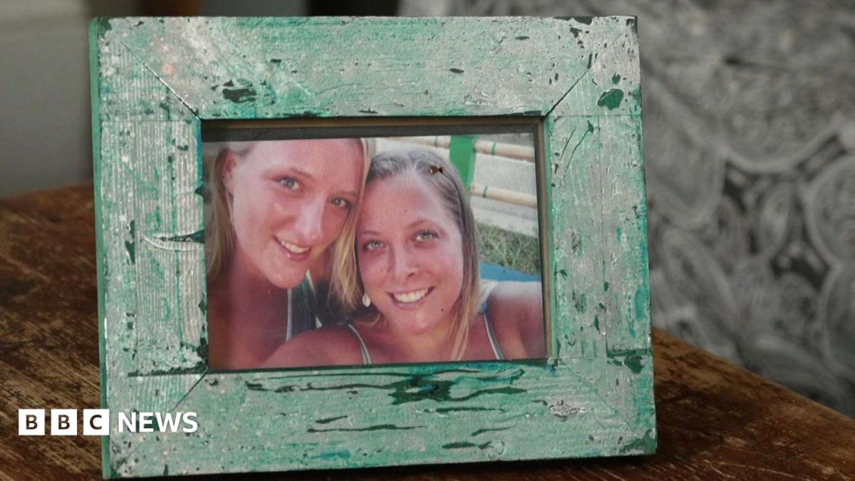 Two smiling blonde women in a photo within a green frame on a wooden desk