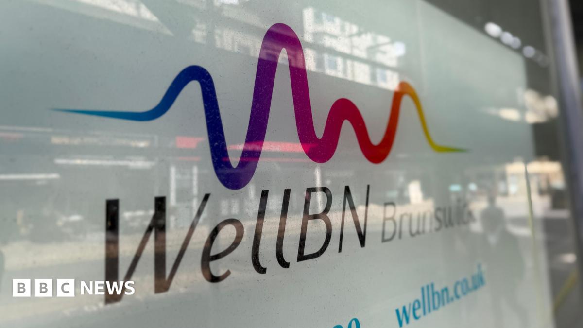 An image of the WellBN clinic sign in Brunswick, Brighton. In the window you can see a reflection of a child walking passed and some shops on the road opposite.