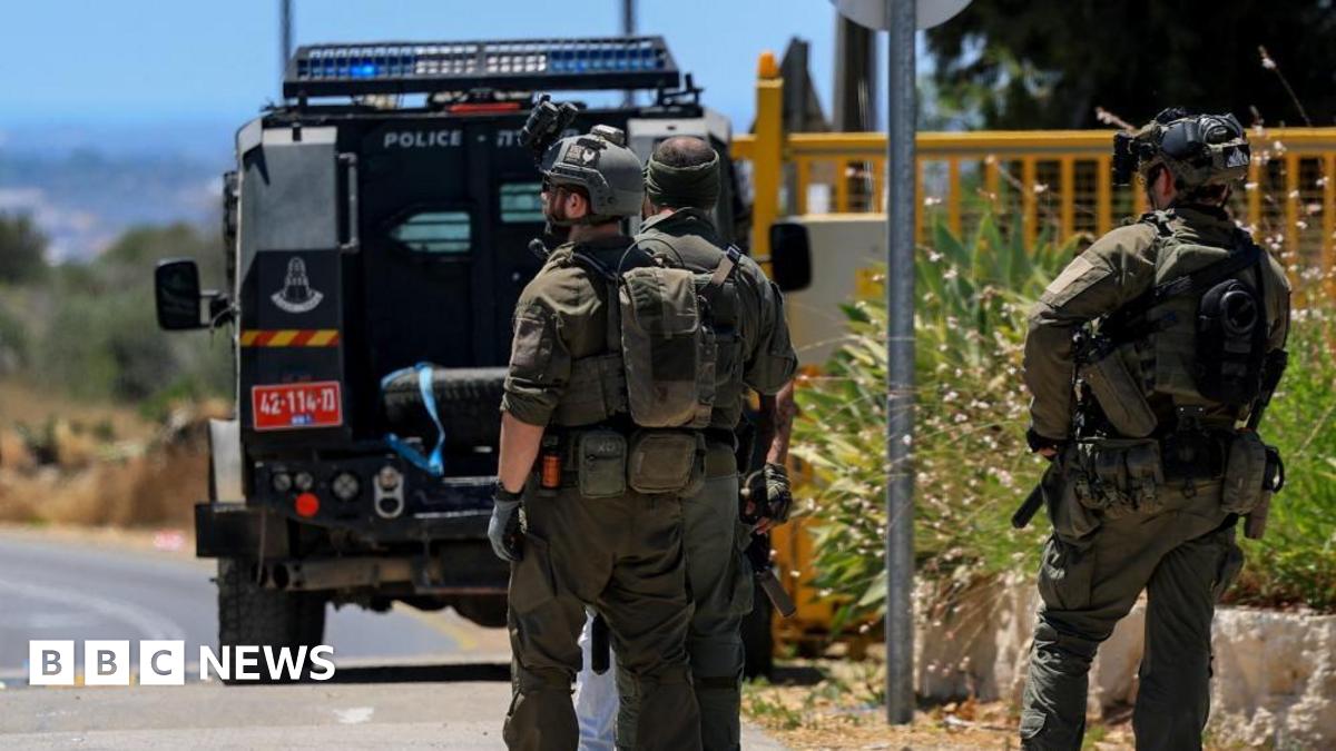 Three Israeli emergency personnel at the scene of the shooting with a police truck in front of them