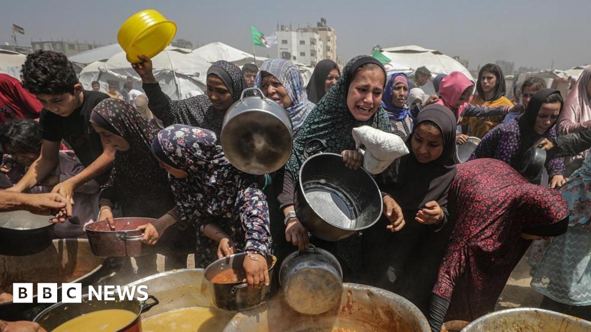 Displaced Palestinians gather to receive a portion of food from a charity kitchen, in Jabalia refugee camp, northern Gaza