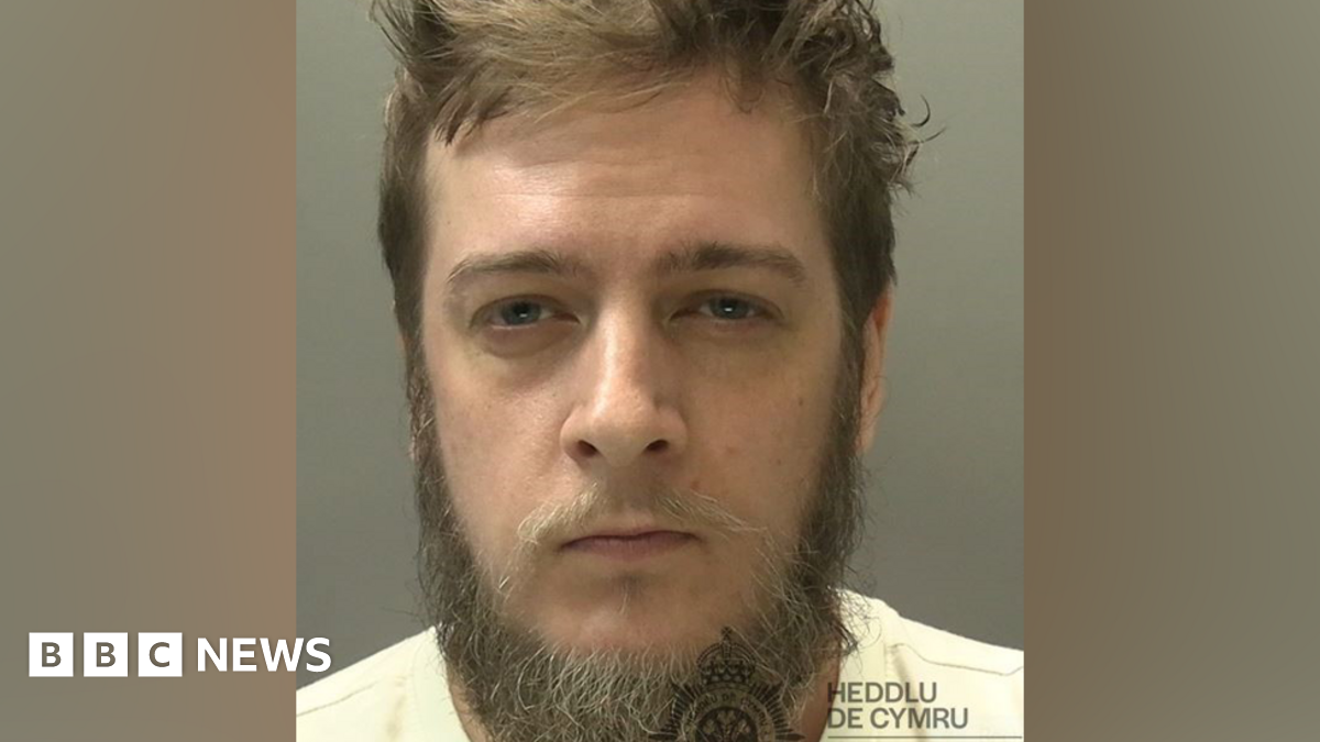 A custody image of a man with a beard and a whispy moustache 