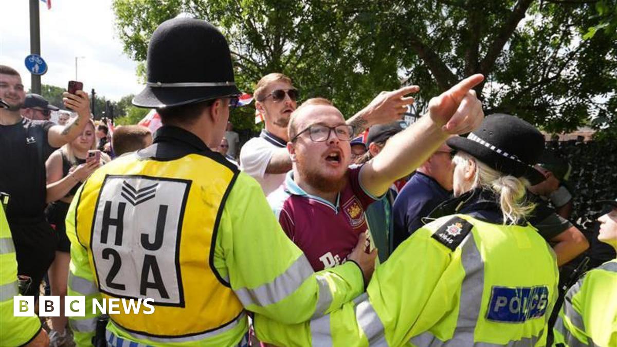 A man at a protest is held back by police. 