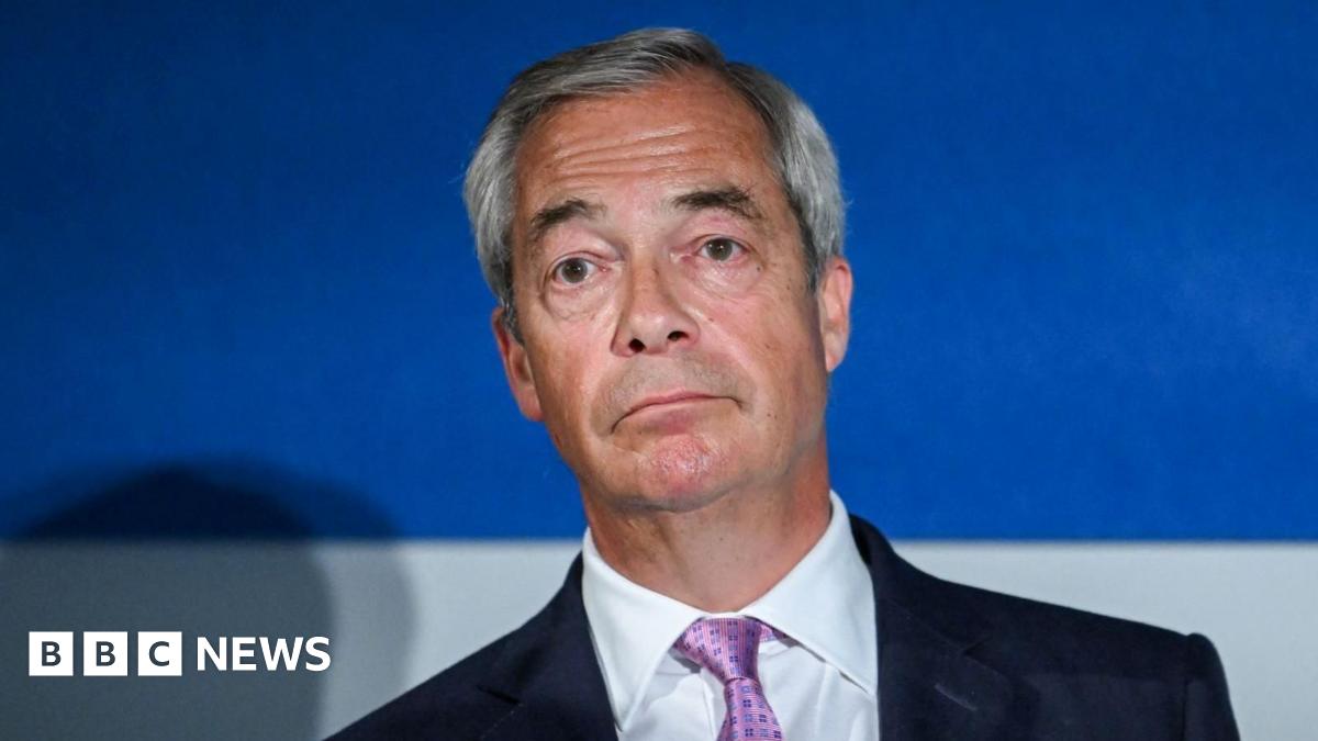 Nigel Farage looking disappointed and facing the camera. He is wearing a black blazer, white shirt and purple tie.