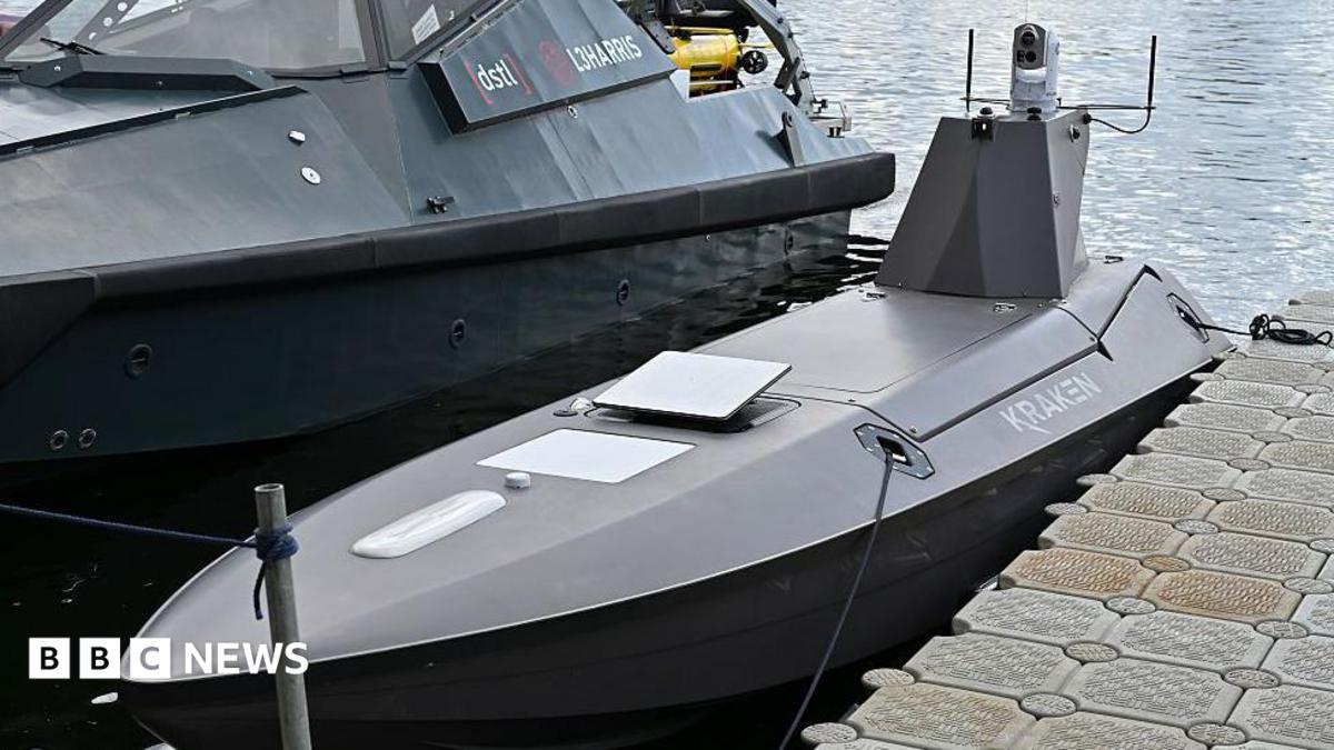 A Kraken K3 Scout high-performance USV drone parked next to a larger boat with water shown behind it