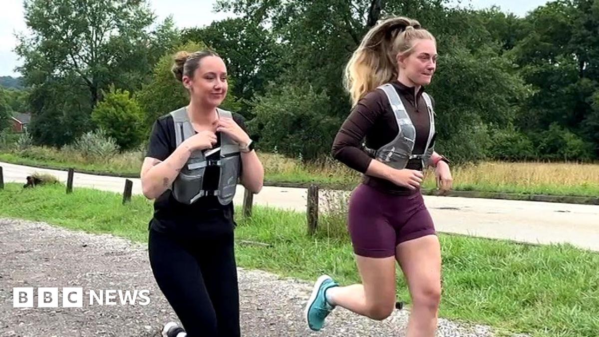Image shows two females running. One is dressed in all black. She has a black short-sleeved top and black leggings on with a grey running vest over the top. She has black Nike trainers on. Her hair is in a bun. The second officer has turquoise trainers...