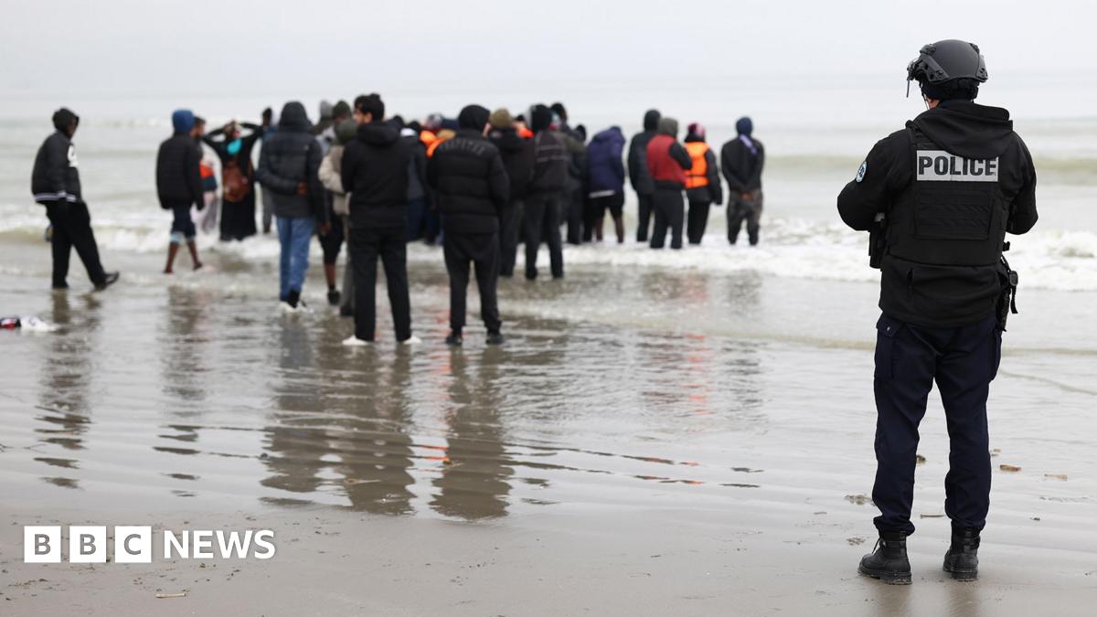 A police officer looks out to sea as a group of people wearing inflatable jackets stand in shallow water in Gravelines earlier this month.