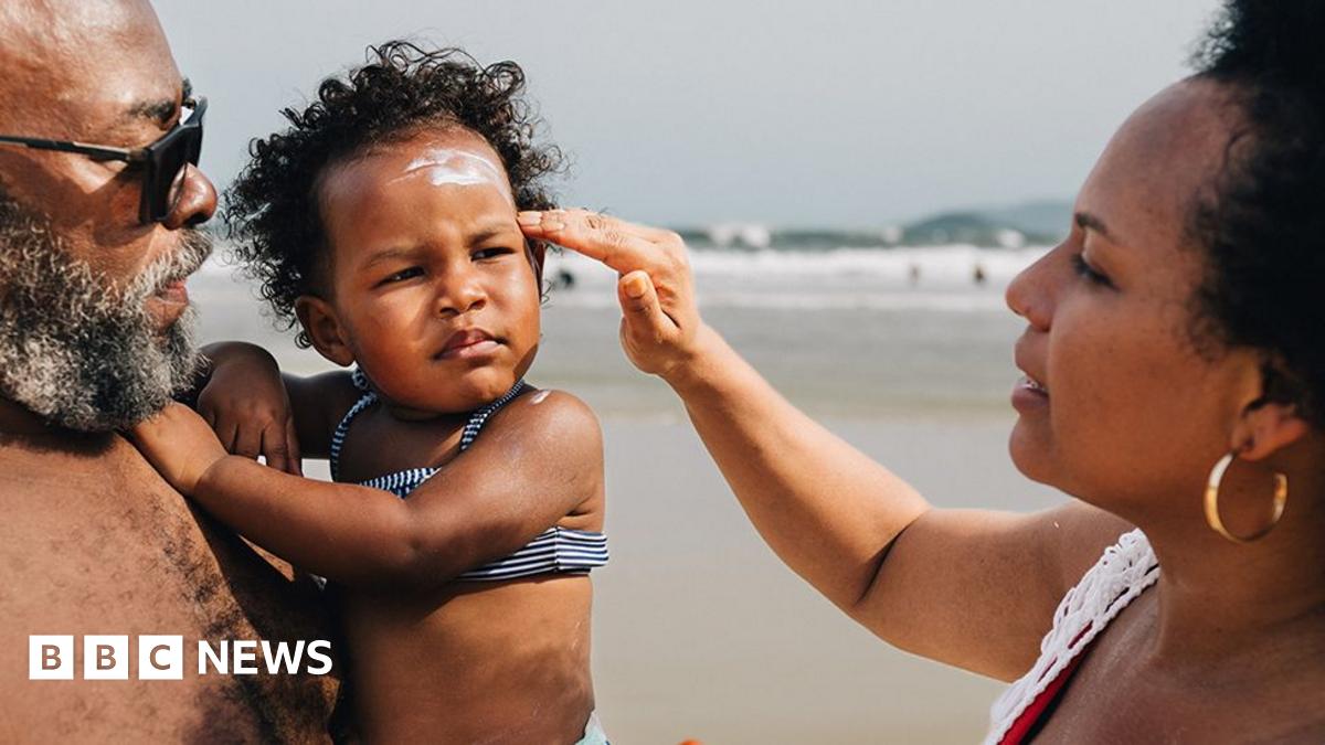 Woman putting sunscreen on small child's face on a beach