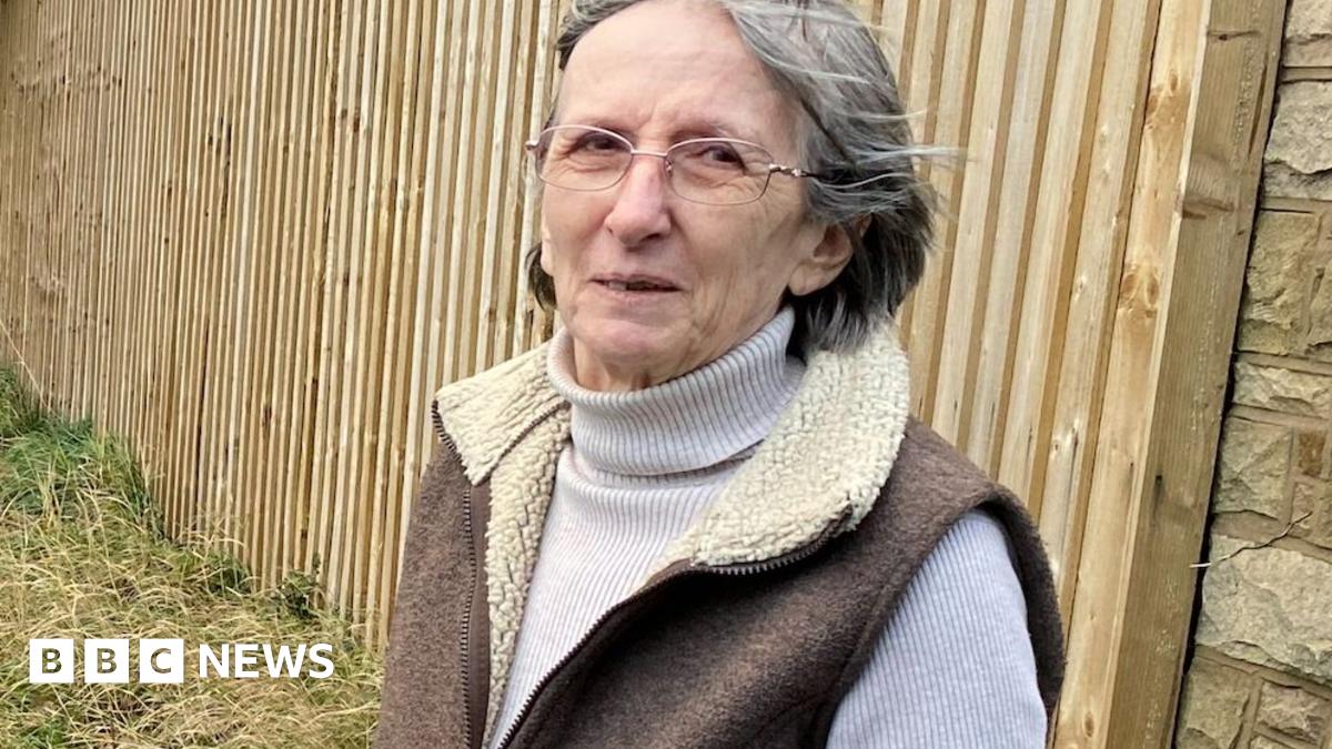Wendy Pleasent. She has grey hair in a bob and is wearing glasses, a polo neck jumper and sheepskin-type gilet