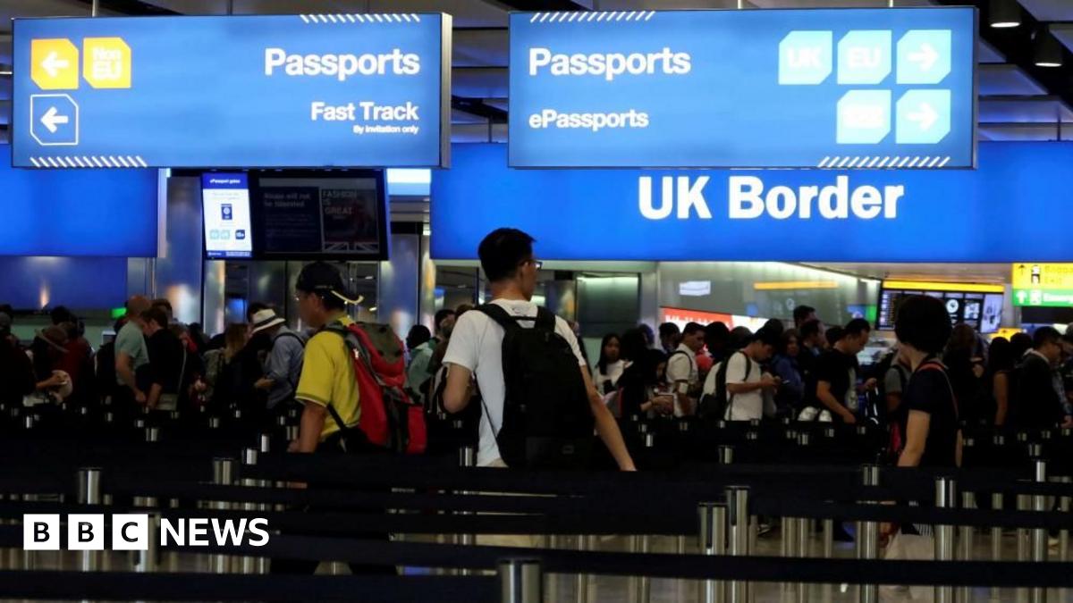 People queue up for passport control at an airport on the UK border. 