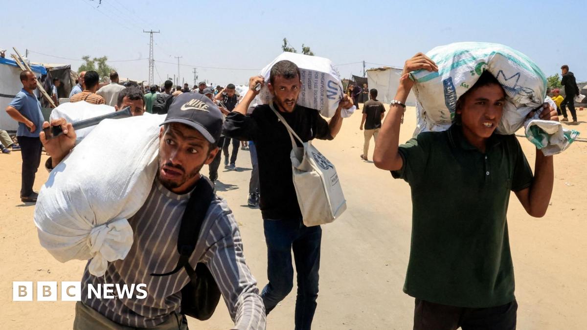 Palestinians carry aid collected from a Gaza Humanitarian Foundation distribution centre in the city of Rafah, southern Gaza (9 June 2025)