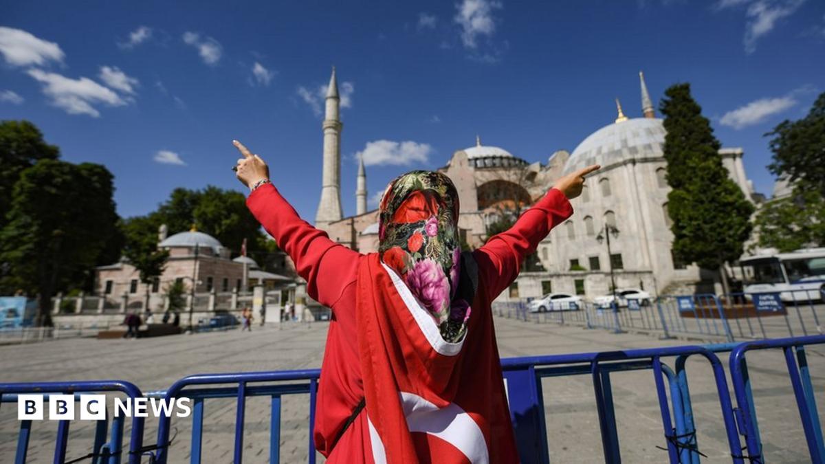 A woman wrapped in a Turkish national flag gestures outside the Hagia Sophia museum on July 10, 2020 in Istanbul as people gather to celebrate after a top Turkish court revoked the sixth-century Hagia Sophia"s status as a museum, clearing the way for i...
