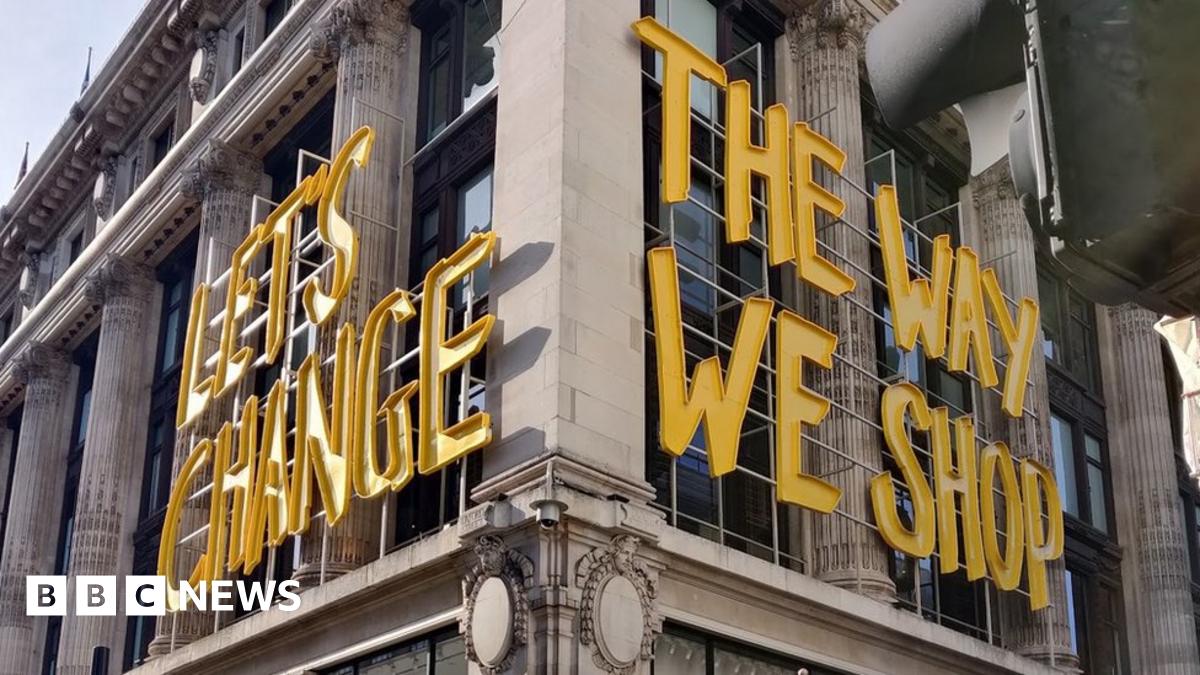 "Let's Change the way we shop" yellow sign onside of Selfridges building