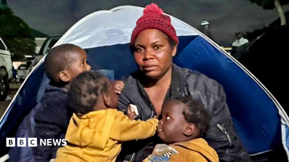 Photo: bbc.co.uk Esnat Joseph, wearing a maroon woollen bobble hat and black jacket, sitting in front of a tent with her baby triplets - two