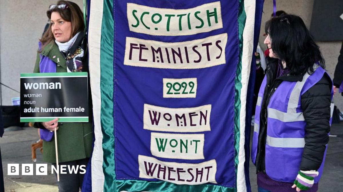 Two women holding up a purple banner with the words 'Scottish Femenists Women Won't Wheesht' on the front in white boxes.