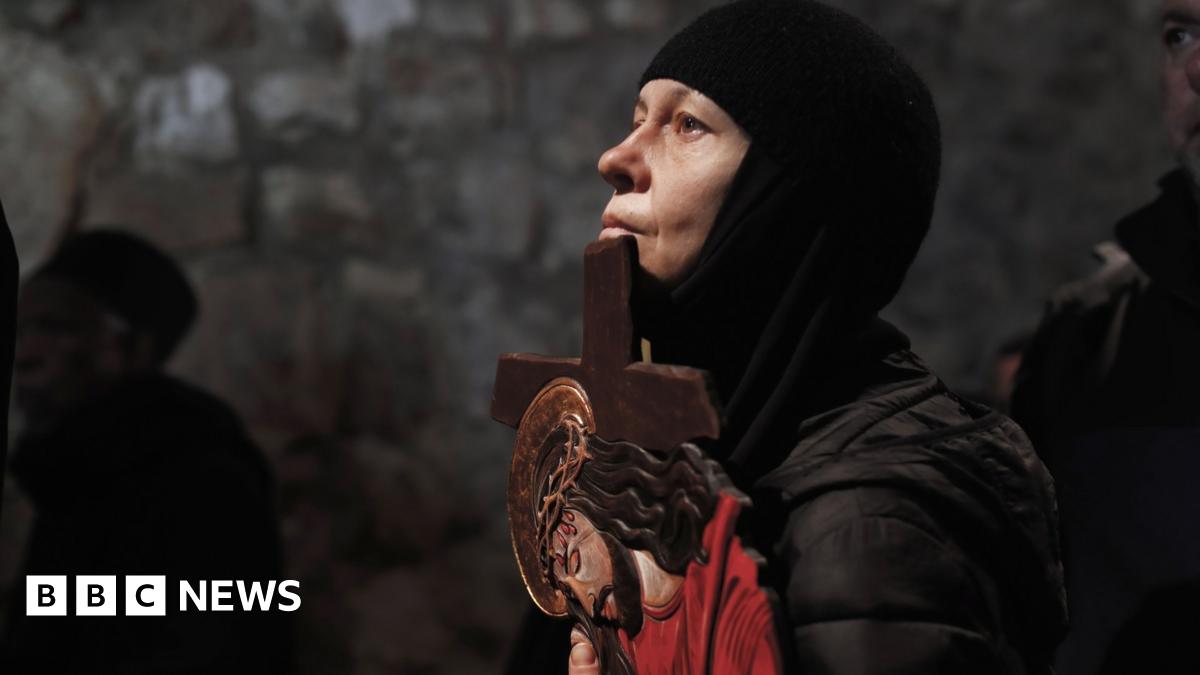 A Christian Orthodox pilgrim holds a cross with a depiction of Jesus