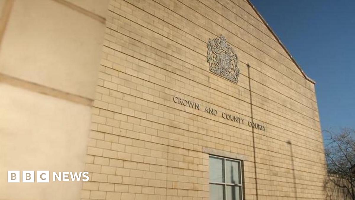 A yellow brick building with "crown and county courts" written on the side. There is blue skies above.