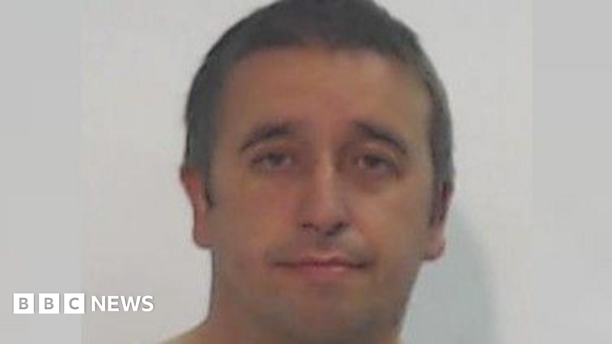 A police mugshot of a round-faced man with short brown hair