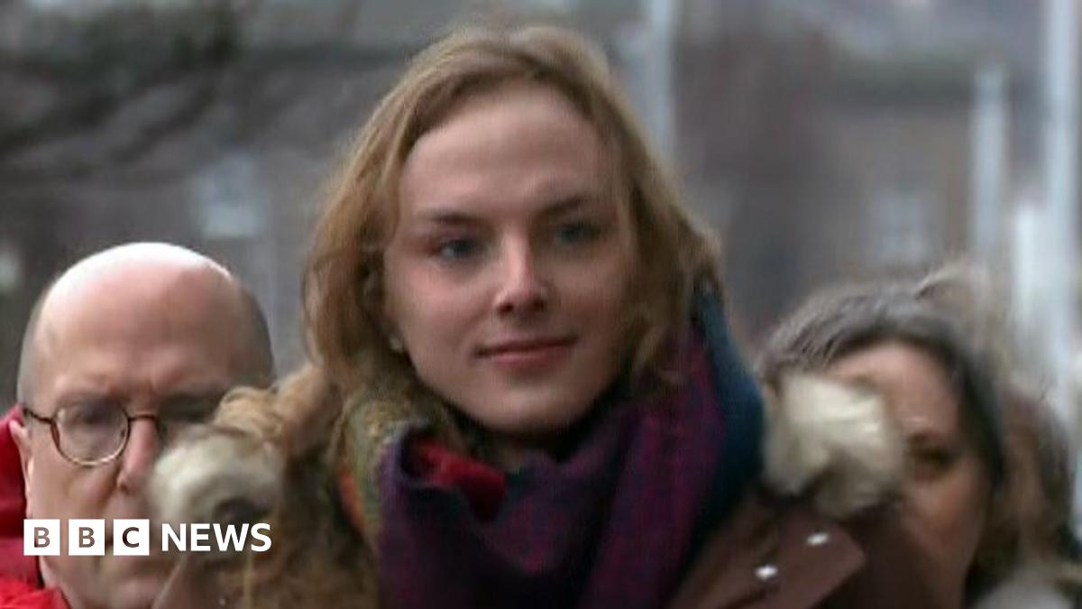 Dr Beth Upton has long brown hair and has a slight smile. The medic wears a colourful scarf and a brown parka and is flanked by two other people.