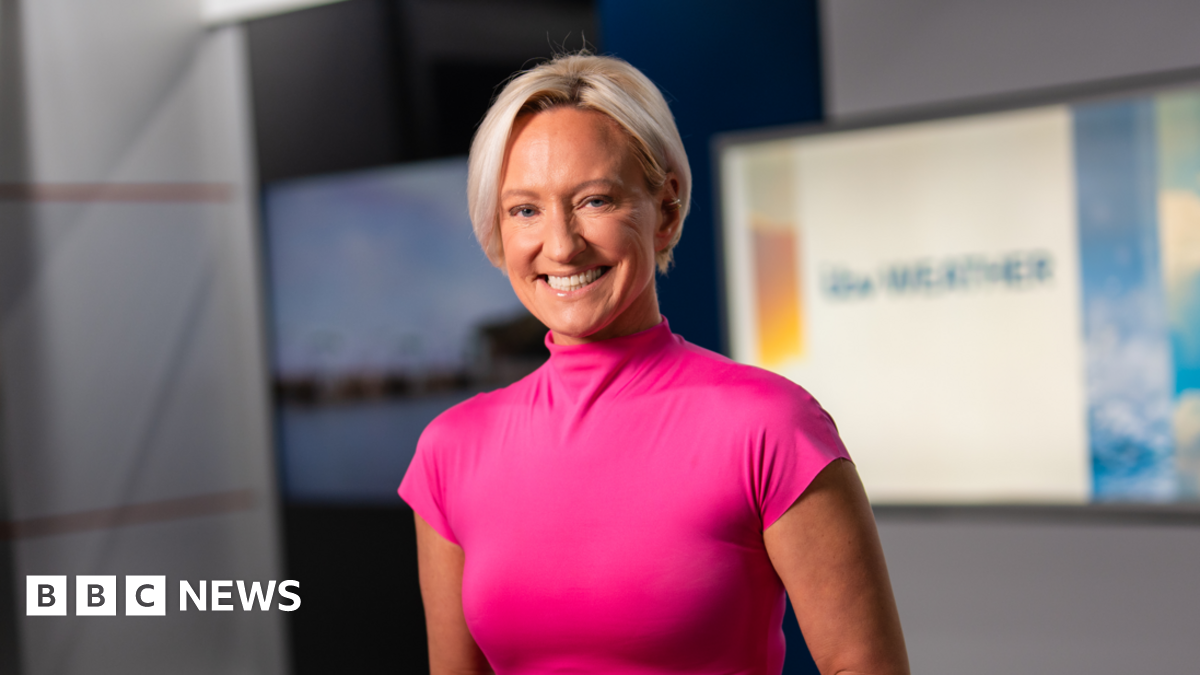 Ruth Dodsworth, with short blonde hair and wearing a pink top, stands in the ITV Wales studio smiling