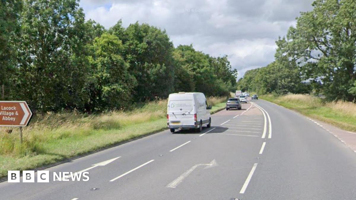 Image of a main road, with a van and a number of cars.  In the background can be seen hedges and grass verges.